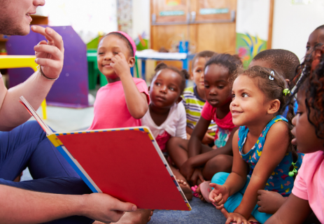 Group of children looking at teacher holding a picture book