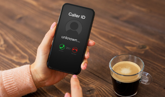 Smartphone with unknown caller on screen, understanding robocalls