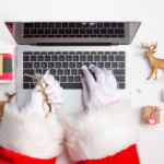 Santa typing on laptop with Christmas decorations