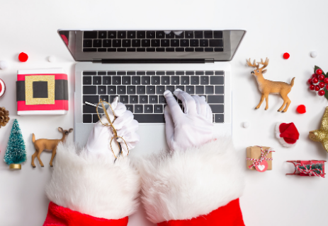 Santa typing on laptop with Christmas decorations