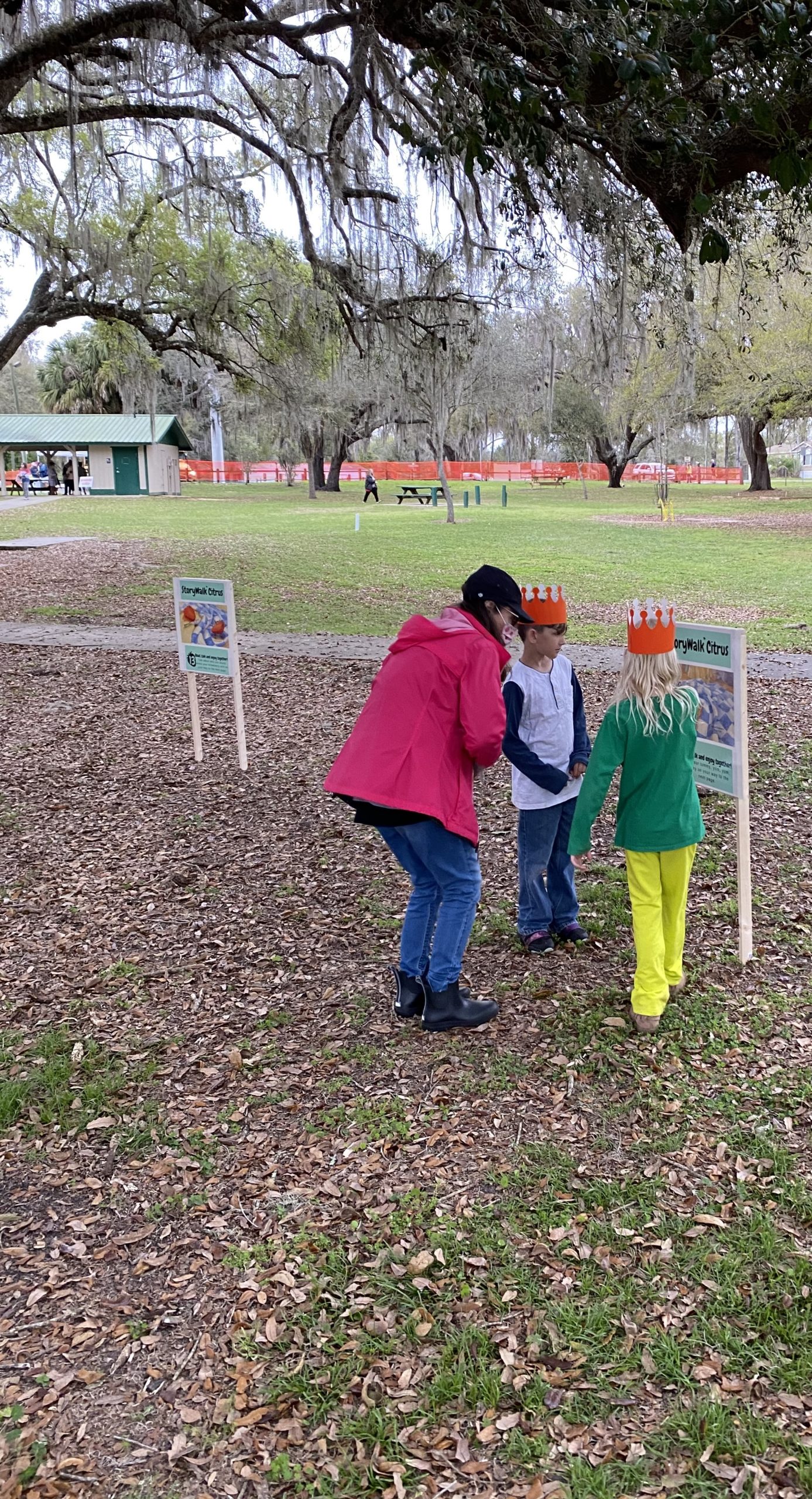 Staff helping 2 children participate in the Storywalk at the Floral City Strawberry Festival