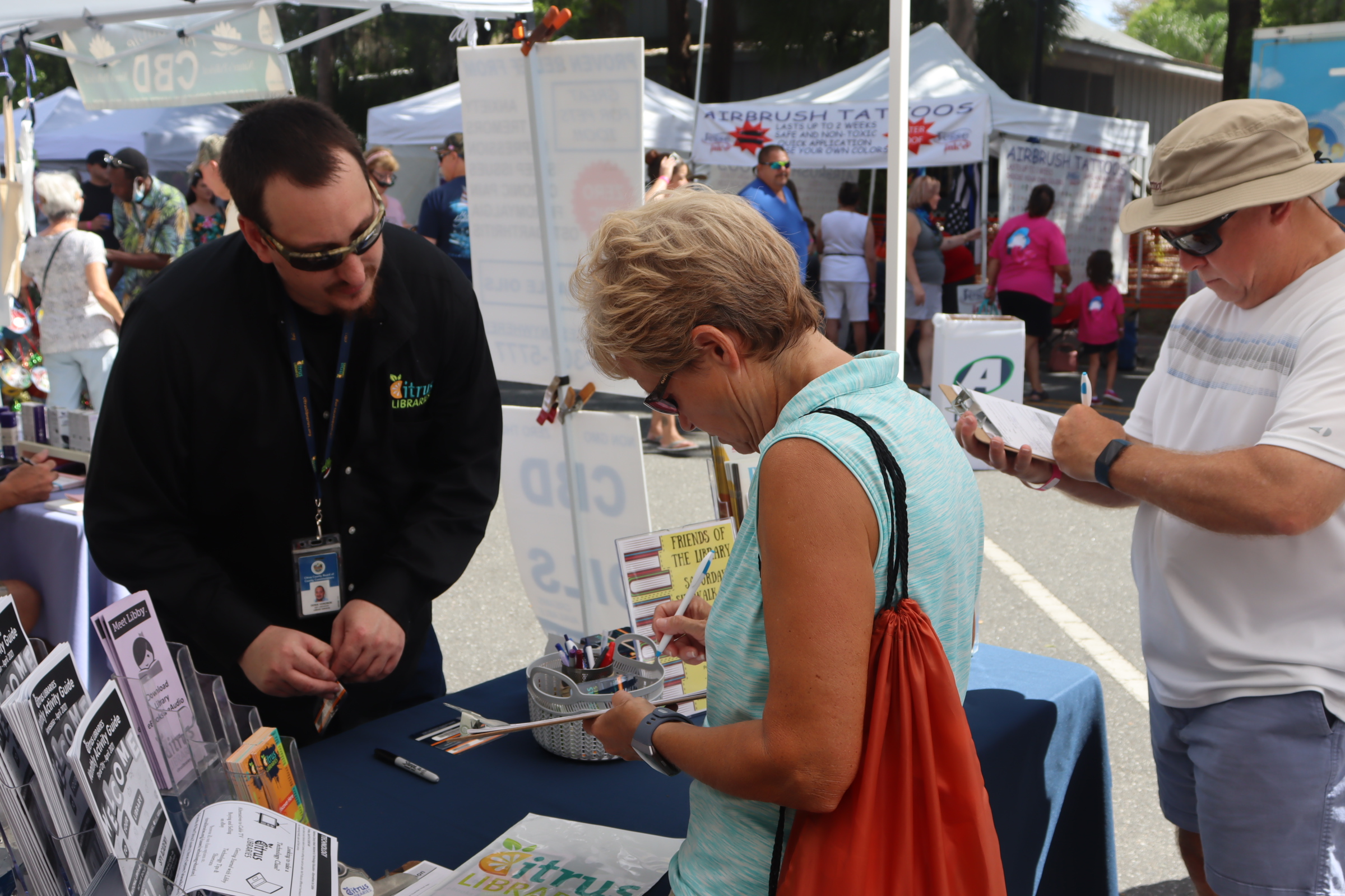 Library staff helping 2 guests apply for new Library cards at the Manatee Festival in Homosassa