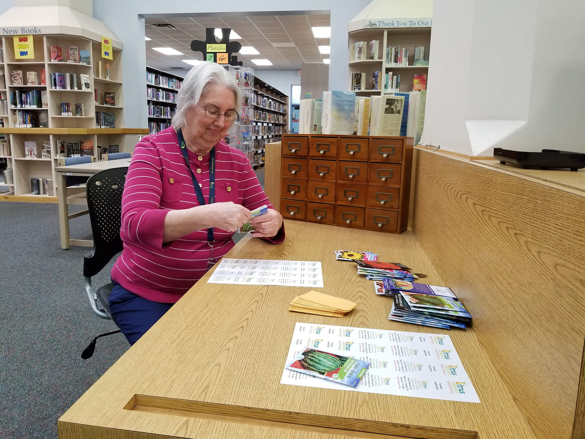 Lakes Region Library Aide Jeri Akins fills seed packets in preparation for the Seed Library debut on Earth Day, April 22, 2022.