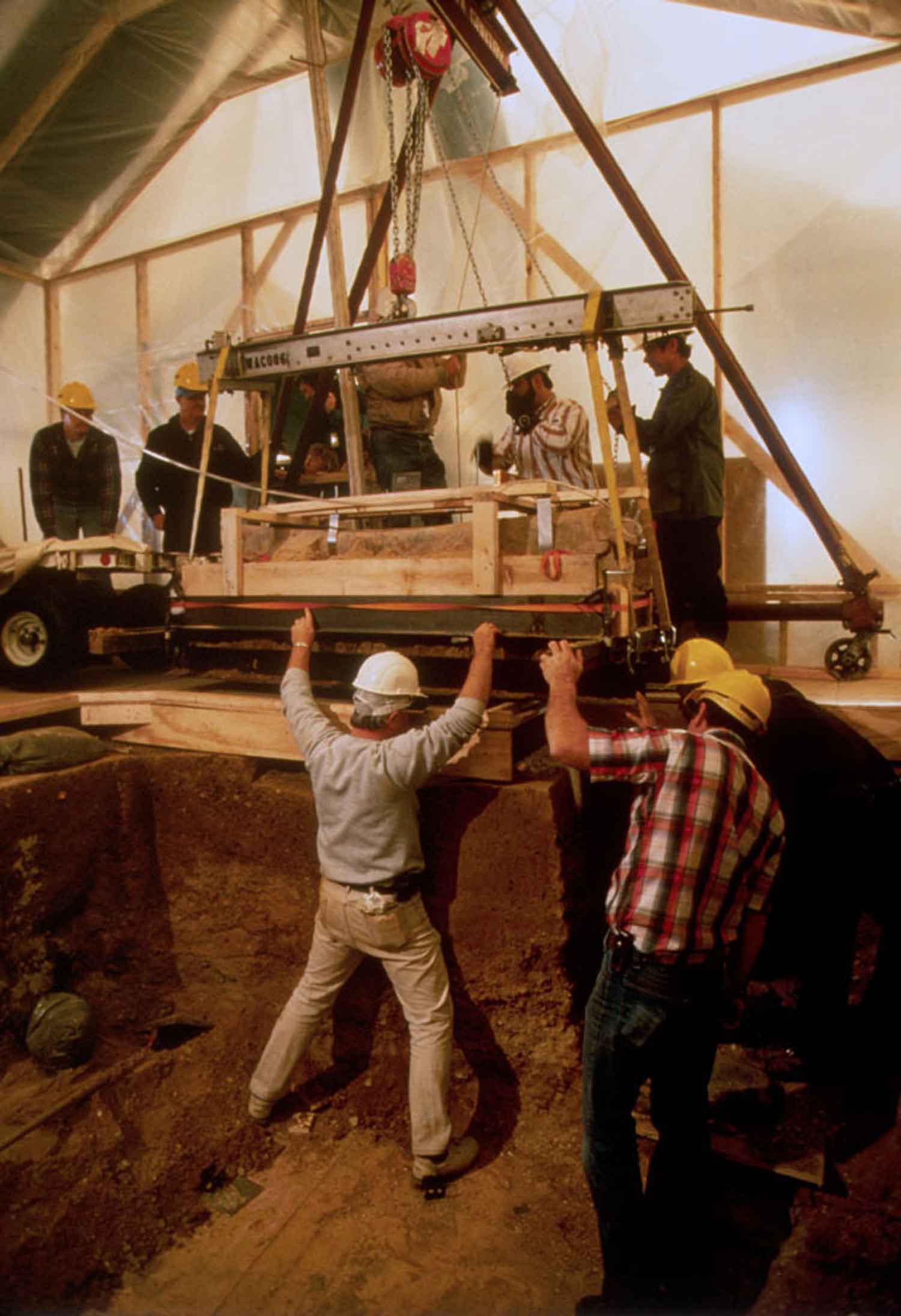 Archaeologists with lead coffin Team of Archaeologists lifting one of the lead coffins from dig sit with a crane