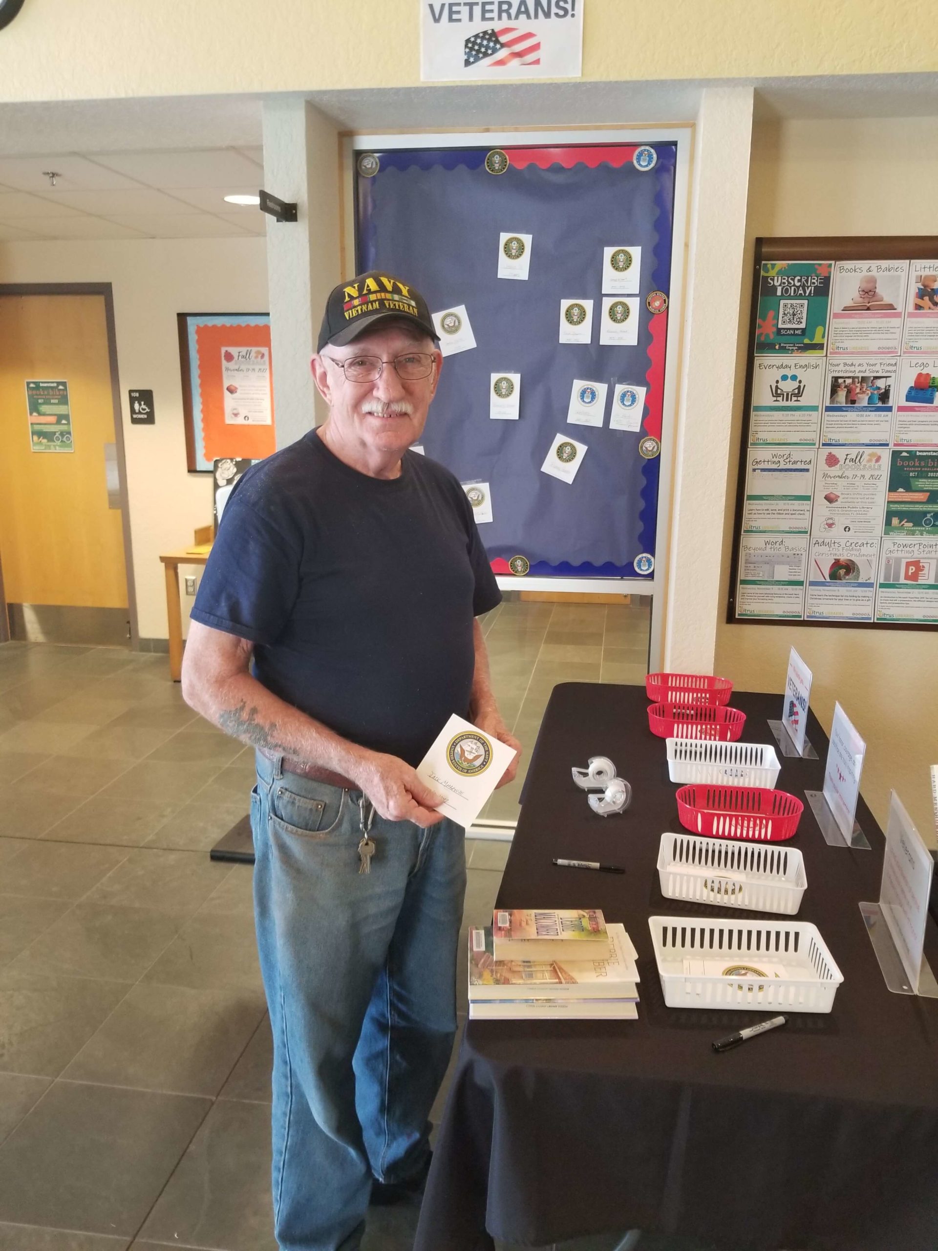 Veteran at the Homosassa Library holding signed placard for Veteran's Day wall