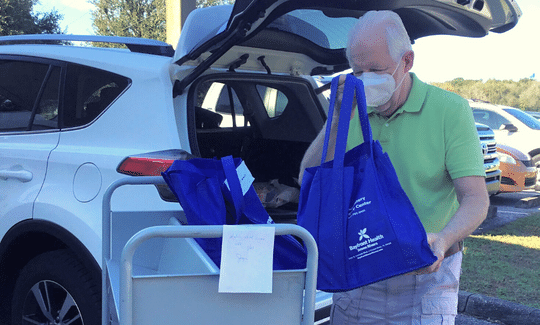 Volunteer loading filled bags with books into vehicle to deliver to to Homebound patrons.