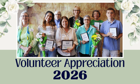 Group photo of volunteers holding award plaques with text Volunteer Appreciation 2026 on neutral green background and floral embellishments