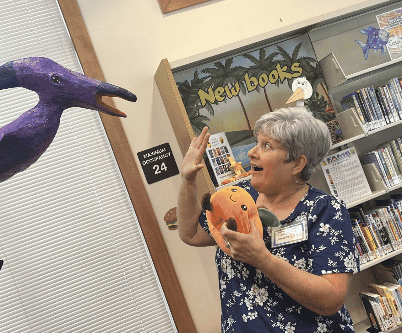 Floral City Library Volunteer Valerie, shocked by paper dinosaur overhead.